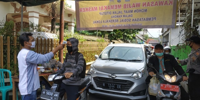 Petugas Kelurahan Mergosono mengecek suhu tubuh para pengendara yang masuk. Per hari ini, Jumat (10/7/2020) Mergosono resmi menerapkan PSBL alias lockdown wilayah. Foto: Ulul Azmi.