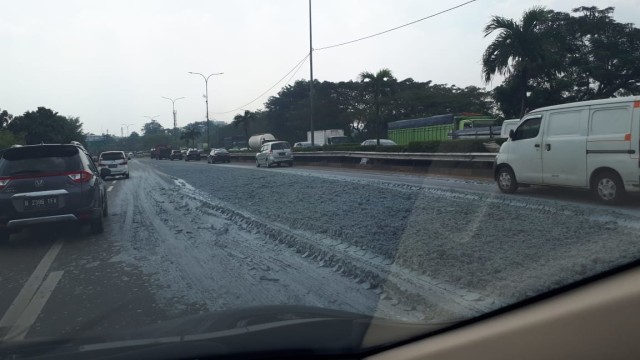 Tumpahan semen yang menutupi jalan tol lingkar luar Jakarta yang mengakibatkan kemacetan. Foto: Aditia Noviansyah/kumparan