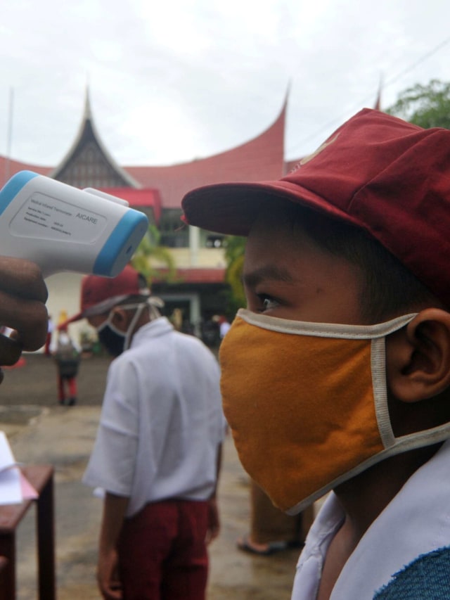 Guru memeriksa suhu tubuh murid saat hari pertana masuk sekolah di SDN 11 Marunggi, Pariaman, Sumatera Barat. Foto: Iggoy el Fitra/ANTARA FOTO