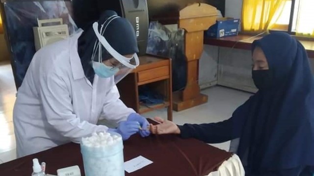 Petugas Puskesmas terlihat fokus mengambil sampel darah  menggunakan alat rapid test kepada salah satu penyelenggara Pemilu di Kabupaten Tolitoli, Sulteng. Foto: Istimewa