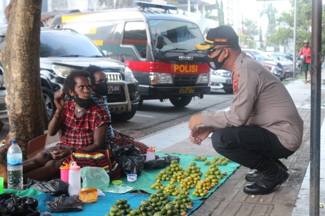 Petugas kepolisian yang tergabung dalam Satgas Aman Nusa II Papua sosialisasi protokol kesehatan kepada pedagang pinang. (Dok: Polda Papua)
