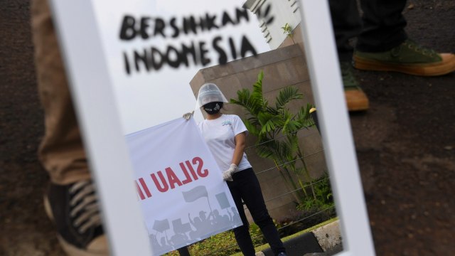 Aktivis Gerakan #BersihkanIndonesia membawa cermin saat mengikuti aksi di depan kompleks Parlemen, Senayan, Jakarta, Selasa (14/7). Foto: Wahyu Putro A/Antara Foto