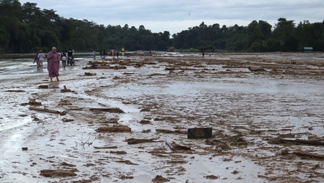 Sejumlah warga melintasi lumpur akibat banjir bandang yang menutupi landasan pacu di Bandara Andi Jemma Masamba, Luwu Utara, Selasa (14/7). Foto: Kemenhub/HO/ANTARA FOTO