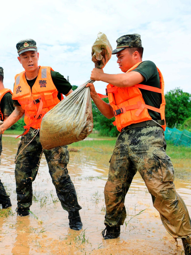Tentara membentuk barisan untuk memindahkan karung pasir untuk tanggul di sepanjang tepi Danau Poyang, China. Foto: Cao Xianxun/Xinhua via AP