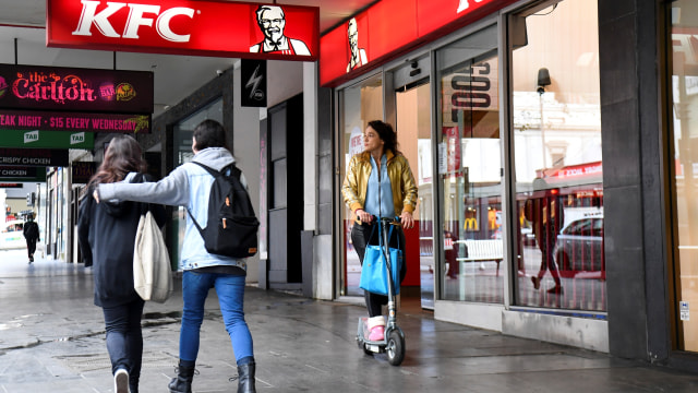 Sejumlah  warga berjalan melewati outlet KFC di distrik pusat bisnis Melbourne, Australia. Foto: William WEST / AFP