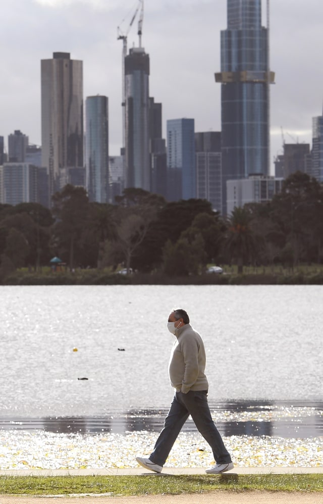 Seorang pria berjalan di sepanjang danau Albert Park di Melbourne, Australia. Foto: William WEST / AFP