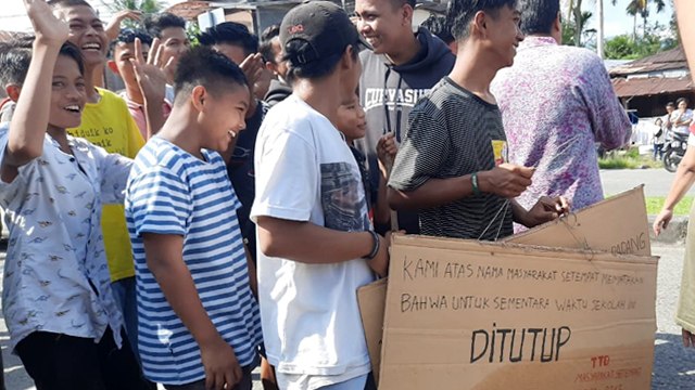 Sejumlah warga membawa kertas yang bertuliskan bahwa SMPN 10 Padang ditutup/disegel (Foto: Adi S/Langkan.id)