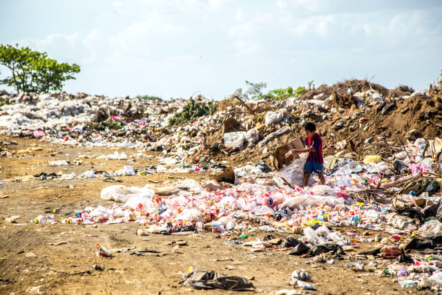 Seorang anak kecil berada di gunungan sampah. (UNSPLASH FOTO/Hermes Rivera)