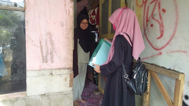 Guru TK Ruman Aceh mengantar buku ajar ke rumah murid. 