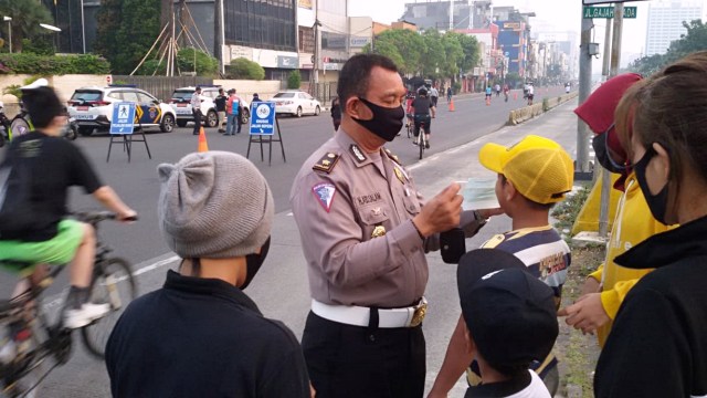 Kanit Lantas Tamansari memberikan masker kepada masyarakat yang tidak menggunakan masker di Traffic Light Ketapang, Jakarta Barat. Foto: Twitter - @TMCPoldaMetro