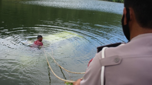 Salah seorang warga berusaha mengikatkan tali ke badan mobil agar bisa ditarik keluar dari dalam air. Foto: Lukman Budianto/kendarinesia.