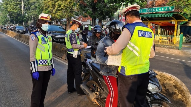 Polisi lalu lintas memberhentikan seorang pengendara sepeda motor melintas jalur Busway di Jalan Buncit Raya, Jakarta Selatan. Foto: Twitter/@TMCPoldaMetro