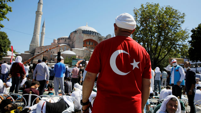 Seorang pria mengenakan baju bermotif bendera Turki menjelang salat Jumat perdana di luar Masjid Agung Hagia Sophia, di Istanbul, Turki, Jumat (24/7). Foto: REUTERS