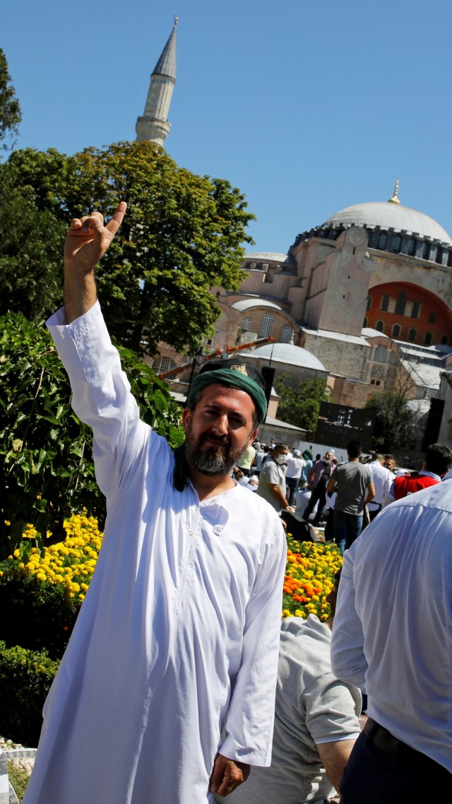 Seorang pria berpose saat menunggu salat Jumat perdana di luar Masjid Agung Hagia Sophia, di Istanbul, Turki, Jumat (24/7). Foto: REUTERS