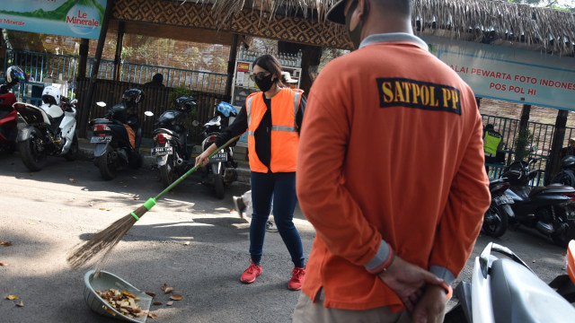Pelanggar protokol kesehatan mendapatkan sanksi kerja sosial menyapu jalan di kawasan Bundaran HI, Jakarta, Minggu (26/7). Foto: Indrianto Eko Suwarso/ANTARA FOTO