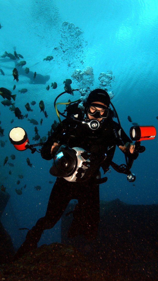Seorang fotografer menggunakan kamera yang dilengkapi underwater strobe untuk memotret di dalam air. Foto: Pixabay