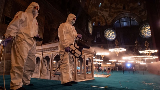 Petugas Kota Fatih menggunakan alat pelindung diri (APD) menyemprot disinfektan di bagian dalam Masjid Hagia Sophia, Istanbul, Turki. Foto: Yasin AKGUL /AFP