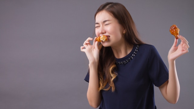 Ilustrasi wanita makan ayam goreng. Foto: Shutterstock