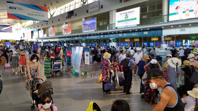 Turis memakai masker saat mereka menunggu untuk check-in untuk keberangkatan di Bandara Da Nang, Vietnam.  Foto: Tran Le Lam/VNA via REUTERS