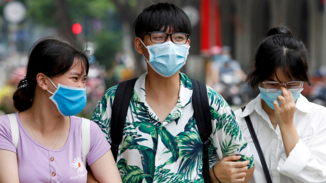 Orang-orang memakai masker saat mereka berjalan di jalan di Hanoi, Vietnam. Foto: Kham/REUTERS