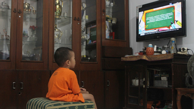 Seorang anak menonton televisi siaran perdana 'Belajar dari Rumah' melaui siaran TVRI di rumah mereka, di Jakarta Selatan, Senin (13/4). Foto: Faisal Rahman/kumpran