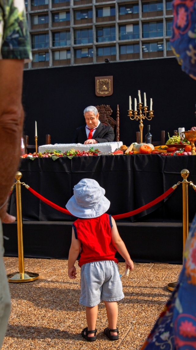 Seorang anak menyaksikan instalasi yang menggambarkan Perdana Menteri Benjamin Netanyahu di lapangan Rabin di Tel Aviv, Israel, Rabu (29/7). Foto: Oded Balilty/AP Photo