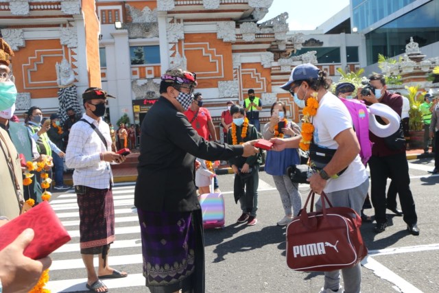 Cok Ace memberikan souvenir untuk wisatawan yang tiba di Bali - IST
