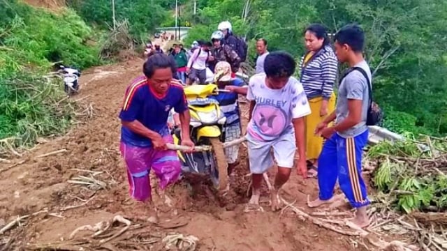 Setiap kendaraan roda dua yang memaksa untuk menyeberangi tumpukan tanah longsor ditandu menggunakan balok kayu. Selasa, (4/8). Foto: Dok istimewa