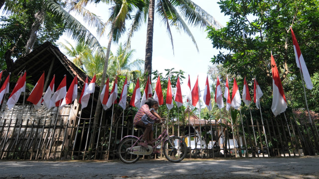 Warga melintas di dekat bendera merah putih terpasang di kediaman Asim di Bayat, Klaten, Jawa Tengah, Rabu (5/8). Foto: Aloysius Jarot Nugroho/ANTARA FOTO