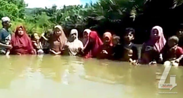 Tangkapan layar dari video yang merekam para wanita dibantu seorang pria menyelam ke dalam sungai. Video tersebut diduga sebuah ritual. | Sumber Foto:Istimewa