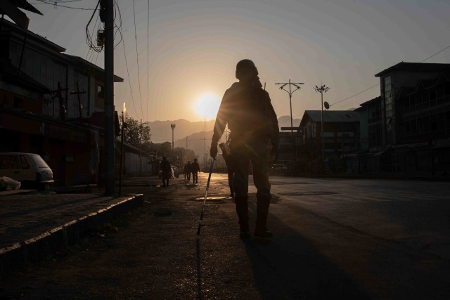 Siluet tentara paramiliter India berpatroli di jalan sepi saat peringatan setahun keputusan India untuk mencabut semi-otonomi wilayah yang disengketakan di Srinagar, India. Foto: Dar Yasin/AP Photo