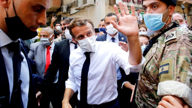 Presiden Prancis Emmanuel Macron melambai kepada warga saat dia mengunjungi jalan yang hancur di Beirut, Lebanon, Kamis (6/8). Foto: Thibault Camus/Pool via REUTERS