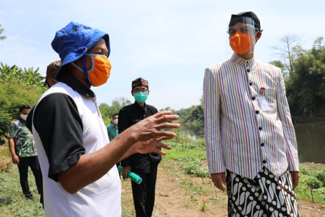 Gubernur Jawa Tengah, Ganjar Pranowo bersama warga yang tak lain kakek petani ketika sidak di kawasan Sungai Bengawan Solo di Karanganyar, Jawa Tengah
