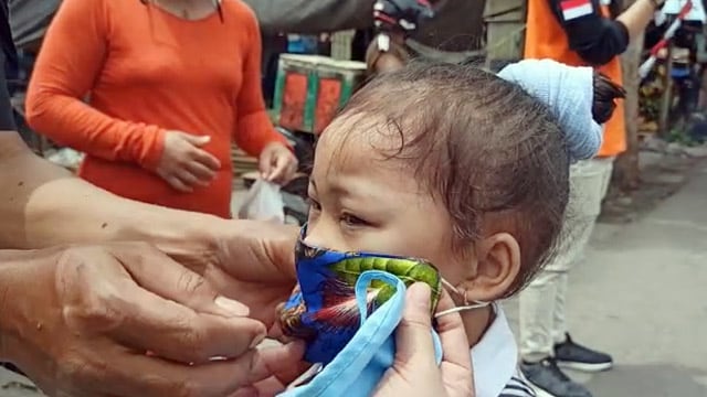 Seorang anak di Kota Bitung diberikan masker untuk melindungi dari penyebaran virus corona