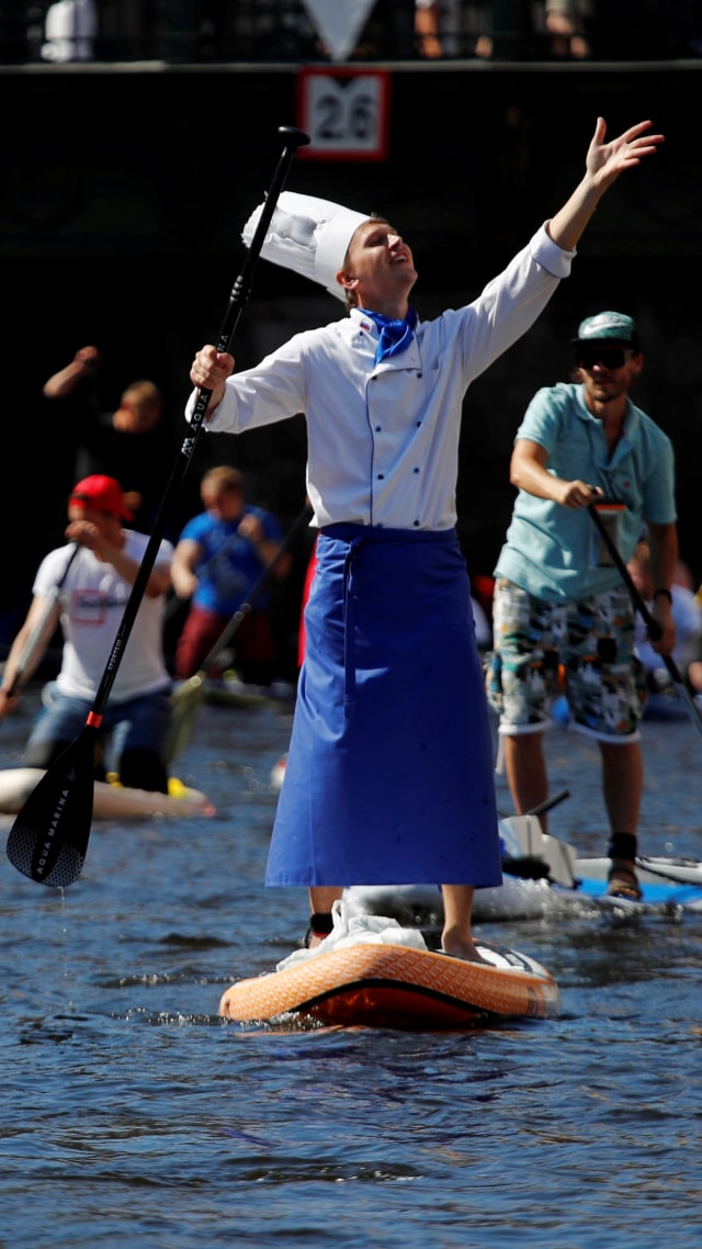 Peserta memakai kostum koki saat mengikuti festival stand up paddle boarding Fontanka-SUP di Kanal Griboyedov, di Saint Petersburg, Rusia, Sabtu (8/8). Foto: Anton Vaganov/REUTERS