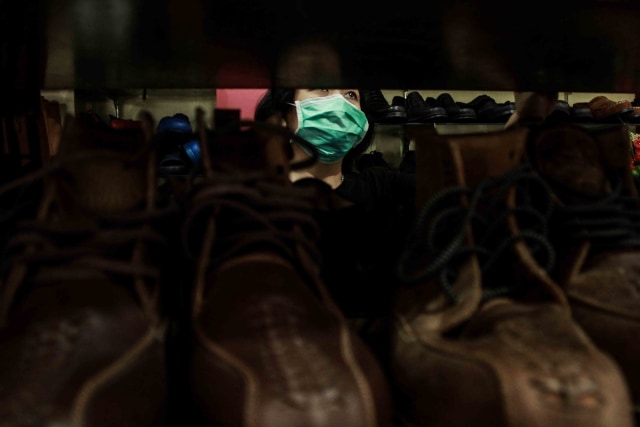 Rini menata sepatu di toko miliknya, yang ada di jalan Bogor, Kota Malang.
