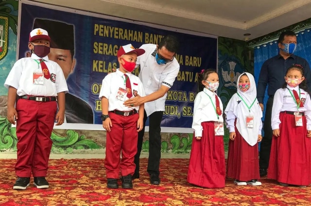 Wakil Wali Kota Batam, Amsakar Achmad menyerahkan searagam gratis kepada pelajar SD secara simbolis. Foto: Zalfirega/kepripedia.com