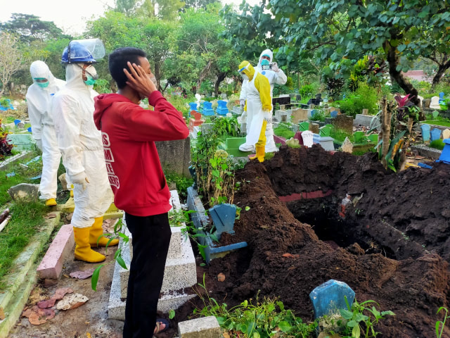 Sejumlah warga diperbolehkan turut andil dalam proses pemakanan jenazah COVID-19 di salah satu TPU Kota Malang. Bahkan juga boleh salat di dekat makam. Foto: UPT PPU Kota Malang.