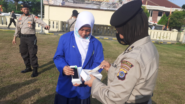 Tri Novi Rahmadani, siswi kelas 8 SMP N 2 Panggang Gunungkidul, saat menerima HP dari anggota Polisi Wanita (Polwan) Polres Gunungkidul, Jumat (14/8/2020). Foto: Erfanto/Tugu Jogja.