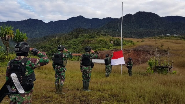 Anggota TNI dari Satgas Yonif Raider 323/Buaya Putih Kostrad kibarkan bendera Merah Putih di distrik Mugu, Nduga, Papua.  Foto: Dok. Istimewa