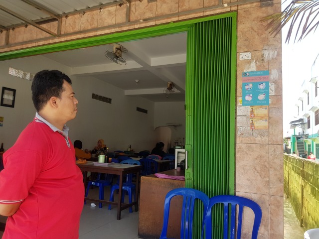 salah satu pegawai rumah makan yang sedang seksama melihat imbauan poster