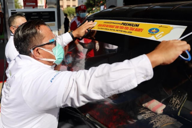 Asisten II Setda Aceh, Teuku Ahmad Dadek, memasang stiker pada mobil yang berhak mendapatkan BBM Bersubsidi, Rabu (19/8). Foto: Suparta/acehkini