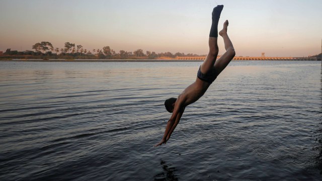 Seorang anak melompat ke Sungai Nil saat cuaca panas di Mesir. Foto: Mohamed Abd El Ghany/Reuters