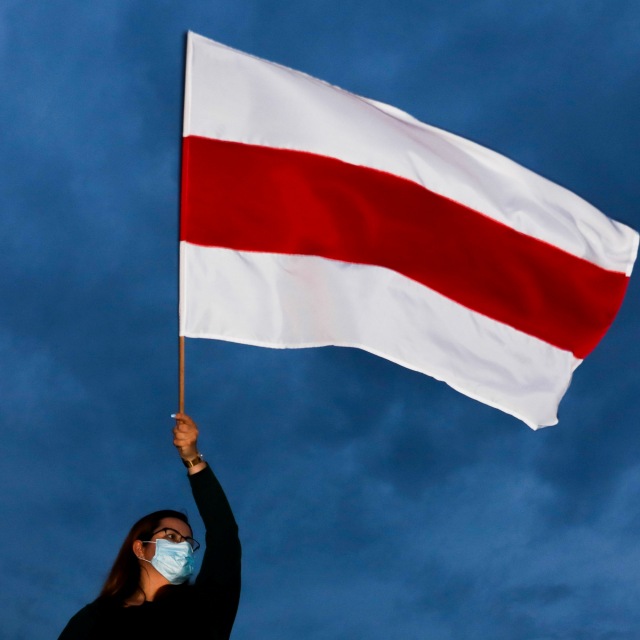 Demonstran mengibarkan Bendera oposisi Belarusia saat demonstrasi oposisi untuk memprotes hasil pemilihan presiden, di Krakow, Polandia (18/8). Foto: Jakub Porzycki/Agencja Gazeta via REUTERS