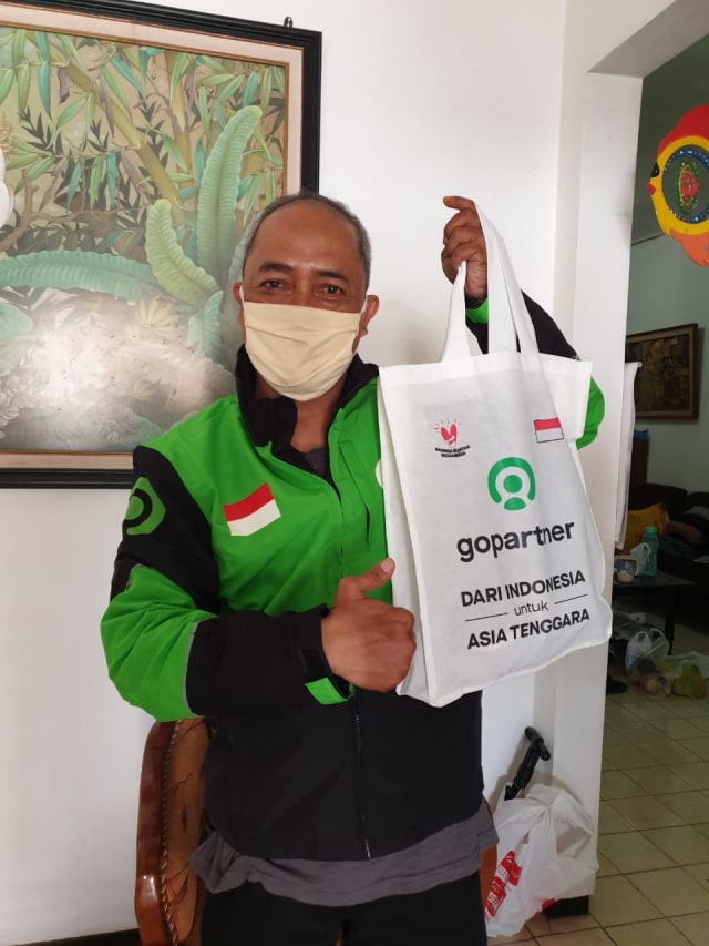 Driver Jempolan, Mbah Wuri, saat menerima penghargaan berupa atribut driver Gojek dari Vietnam dan Thailand yang sekaligus menjadi simbol integrasi Gojek di 4 negara Asia Tenggara. Foto: Gojek