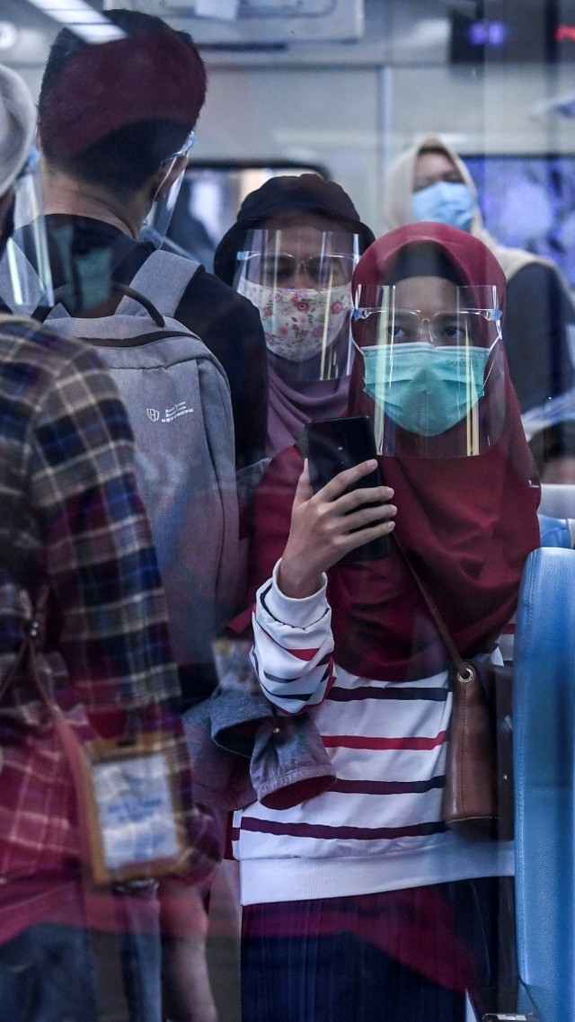 Penumpang menggunakan faceshield dan masker saat menaiki Kereta Api Turangga tujuan Surabaya Gubeng di Stasiun Gambir, Jakarta, Kamis (20/8). Foto: Hafidz Mubarak A/ANTARA FOTO