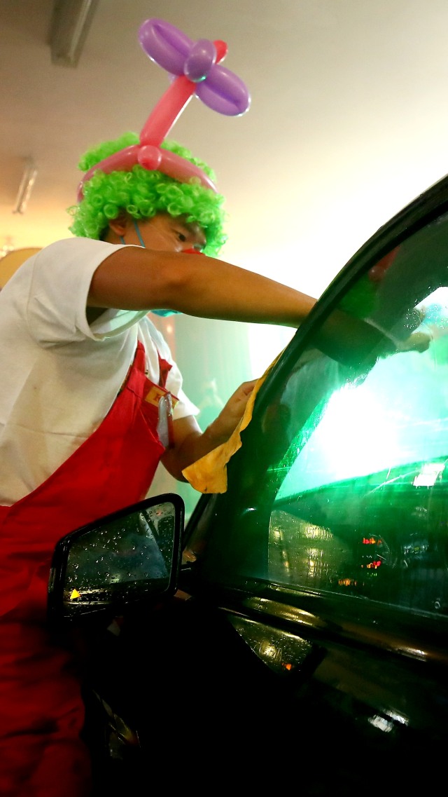Badut dengan kostum lengkap membersihkan mobil di tempat pencucian mobil di Munich, Jerman. Foto: Michael Dalder/REUTERS