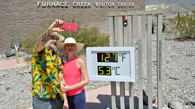 Pengunjung dari Las Vegas berfoto selfie di depan layar bertuliskan 127 derajat Fahrenheit (52,8 Celsius) di Furnace Creek Visitors Center di Death Valley. Foto: David Becker/Reuters