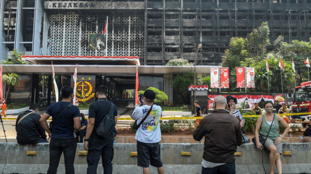 Warga menyaksikan petugas pemadam kebakaran melakukan proses pendinginan di gedung utama Kejaksaan Agung yang terbakar di Jakarta, Minggu (23/8). Foto: Galih Pradipta/ANTARA FOTO