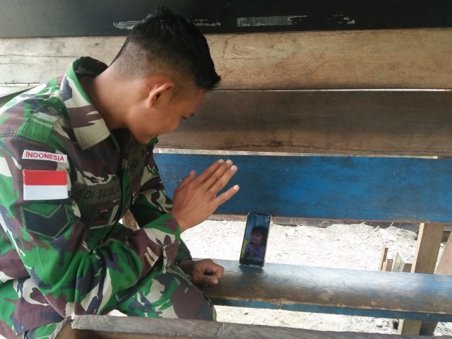 Serka Adhi Susilo, prajurit Yonif MR 413 Kostrad sedang menelpon keluarganya di Jawa Tengah. (BumiPapua.com/Katharina)